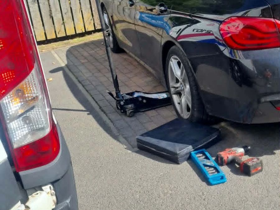 A customer's car on Craig's trolley jack, with his kneeling pad, impact wrench and sockets beside it